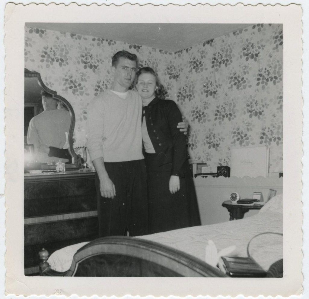 1950s maybe late 1940s vintage photo of a couple in their bedroom with a wallpaper wall