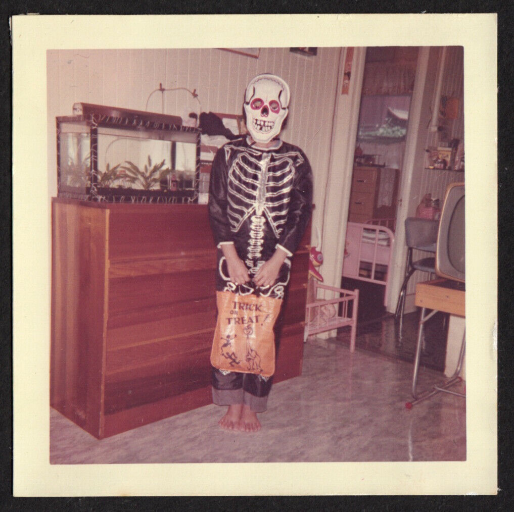 1950s vintage photo of a kid in a mid century house in a skelton halloween costume