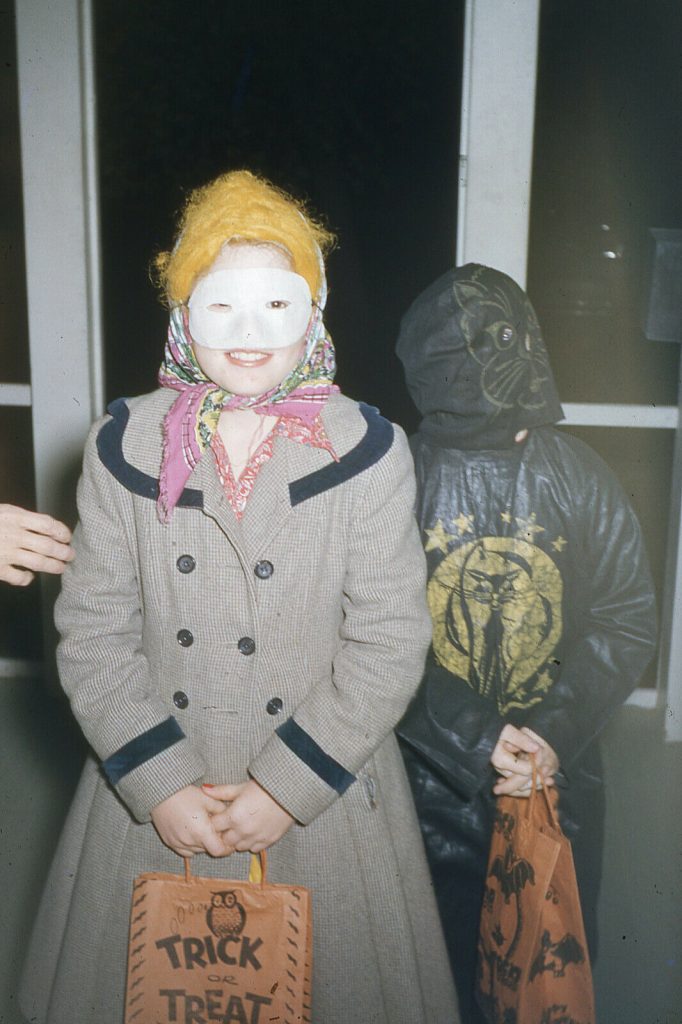 1950s vintage photo of 2 kids in their Halloween costumes posing before they go Trick or Treating. 