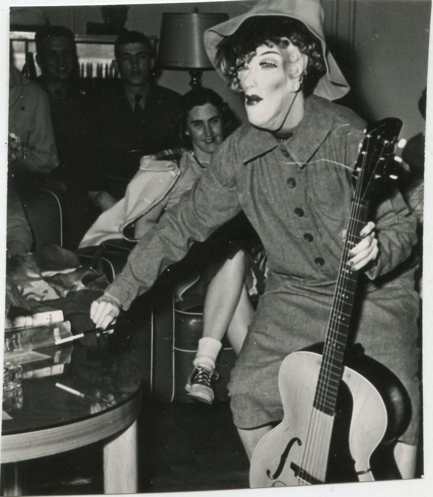 1950s vintage photo of a Halloween party for adults featuring a scary masked musician with guitar 