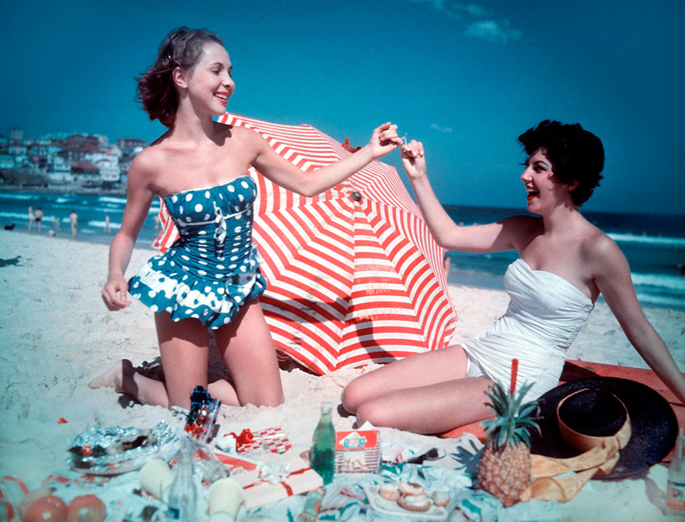 1950s vintage photo of 2 women in 1950s swimsuits having a christmas party on the beach in Bondi Beach, Sydney Australia 1959