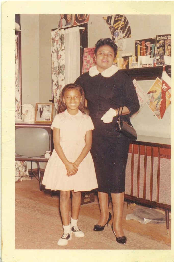 1960s Vintage Photo of a Black mother and her daughter all dressed up in 1960s outfits posing in their home during Christmas. 