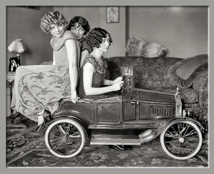 1920s photo of the Brox sisters in 1920s fashions sitting on a toy car