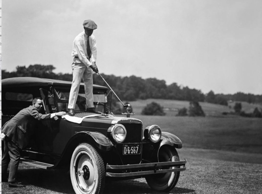 1920s vintage photo from 1924 of a man golfing off her 1920s car.