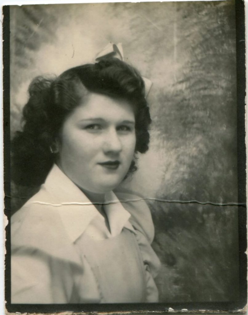 1940s vintage photo booth image of a young woman with a bow in her hair. 