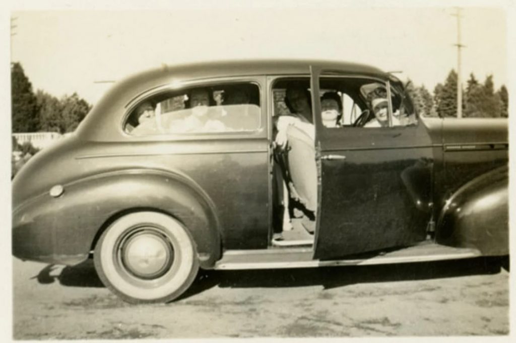 1940s vintage photo of a group of women inside of a car posing for a picture. 