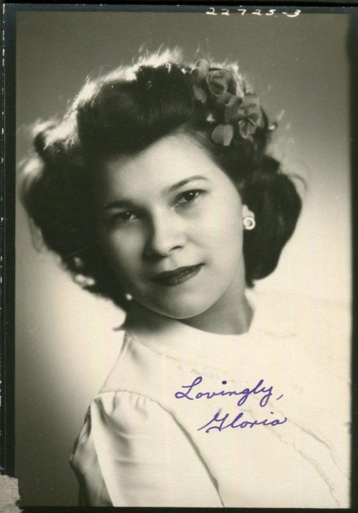 1940s vintage photo of a pretty woman posing for a photo with hair flowers in her 1940s hairstyle