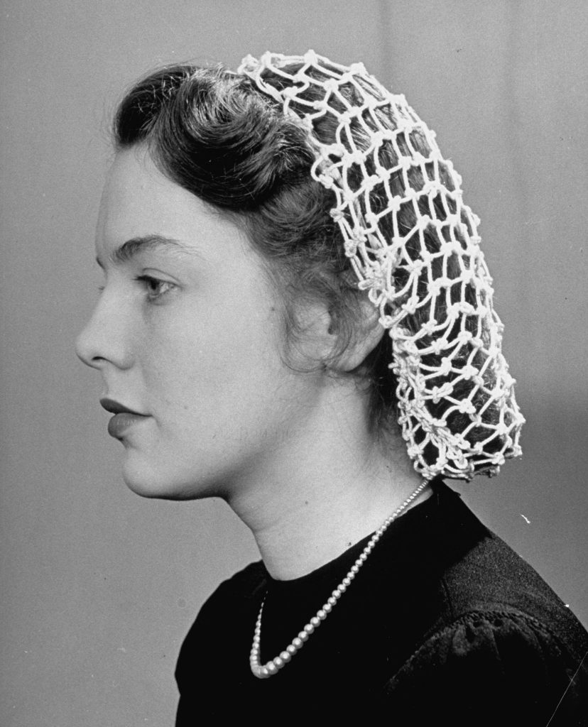 1940s vintage photo of a young woman wearing a snood in her hair. 