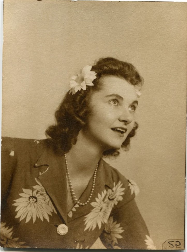 1940s vintage photo of a woman wearing 2 hair flowers in her hair that match her blouse. She is also wearing a string of pearls. Fantastic 1940s Fashions & 1940s Hairstyle Inspiration.