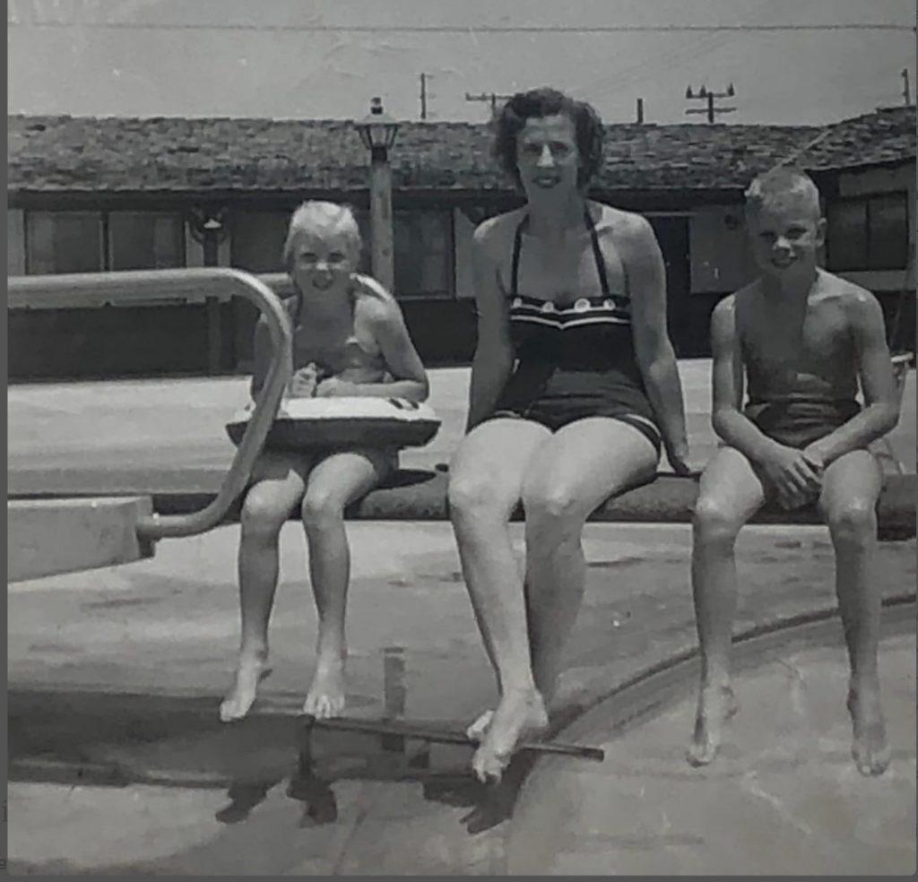 1950s vintage photo of a mother with her two kids posing on a diving board in 1950s swimsuits. July 1959:  at the motel at Disneyland