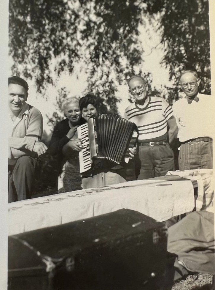 1950s Vintage Photo of a family posing together at a picnic with a young person posing with an accordion. 