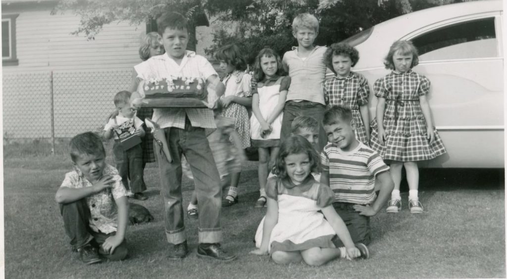 1950s vintage photo of a kids birthday party and the kids posing together with a cake that says jet flyers on it