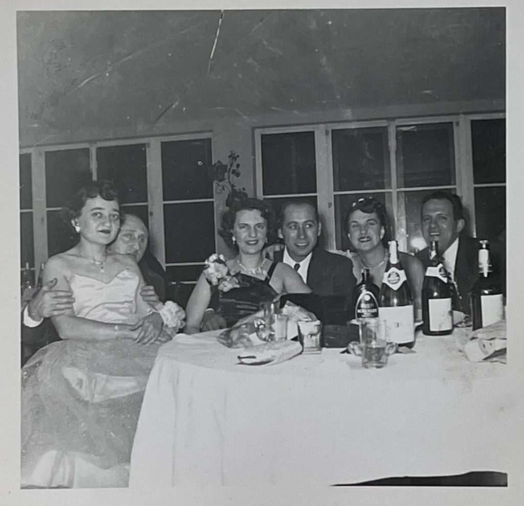 1950s vintage photo of couples in 1950s evening gowns and evenwear posing at a table filled with champagne at a 1950s part