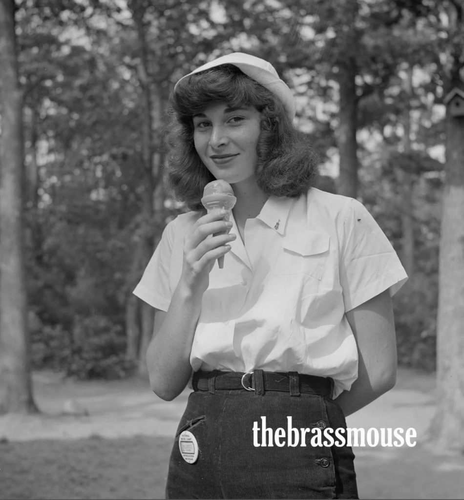 1940s vintage photo of a 1940s teenager / 1940s young woman in 1940s teen fashion / 1940s summer fashion and 1940s hairstyle enjoying an ice cream. 