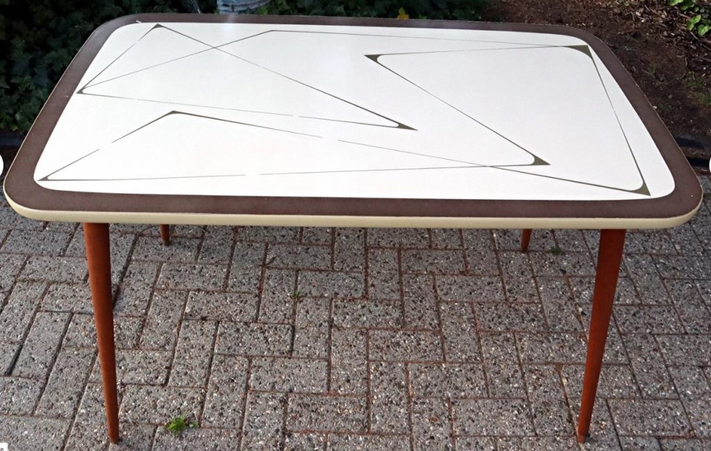 A 1950s wooden kitchen table/ dining table/ living room table with slanted legs and Formica tabletop with a brown line pattern on a beige background. Mid Century Design. 