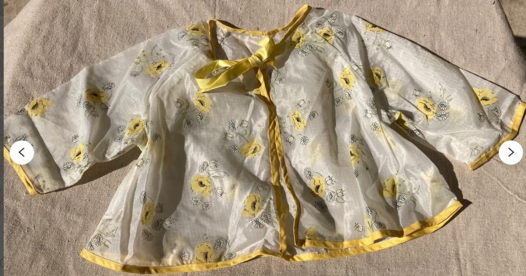 Late 1950s Baby Rain Jacket that features a bright yellow trim with a clear body with yellow poppies and white daisies