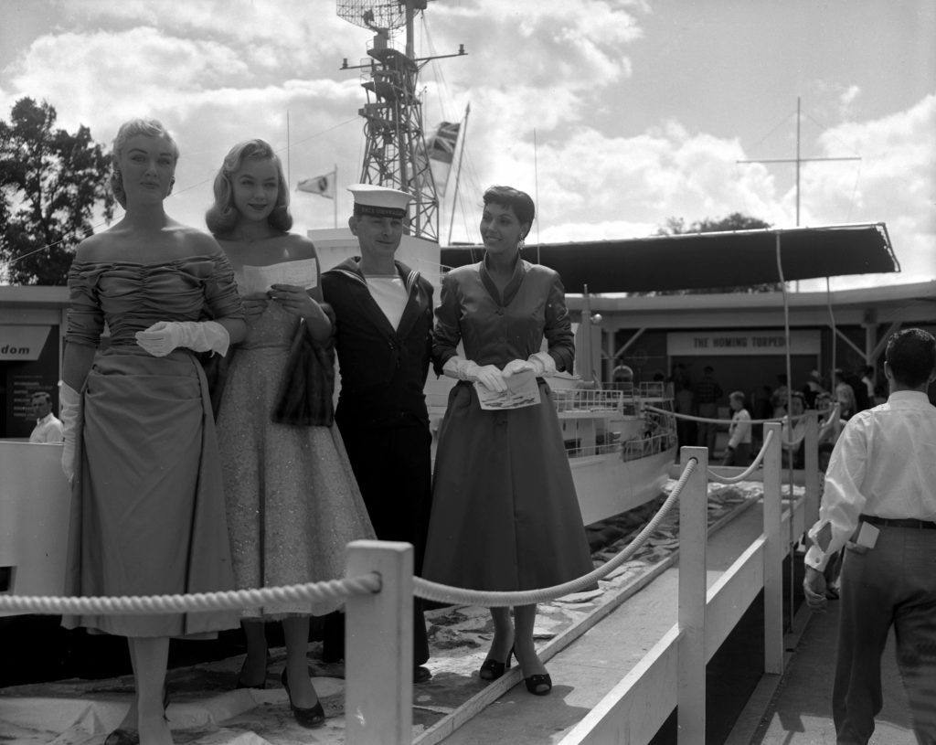 1950s Vintage Photo: 1955 Photo of the Army Exhibit - Navy personnel posed with very stylish women in 1950s fashions and 1950s hairstyles at the Toronto CNE.

