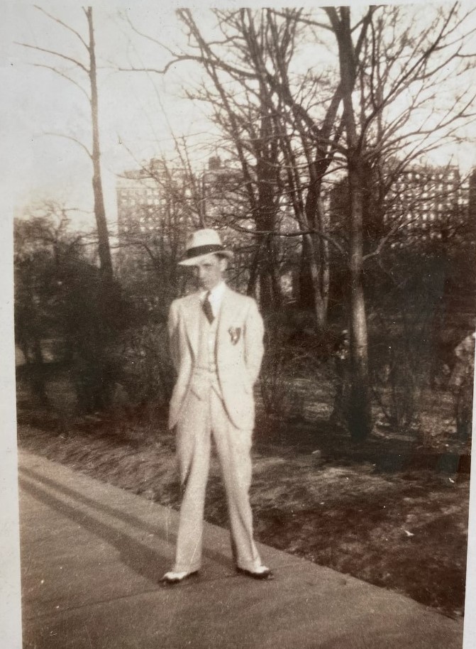 1930s vintage photo of a young man in a 1930s suit, black and white shoes and a 1930s hat posing for a photo. 