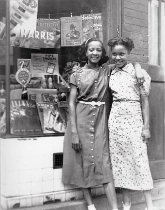 1930s vintage photo of two young women in 1930s dresses posing together in 1930s fashions / 1930s street style. 