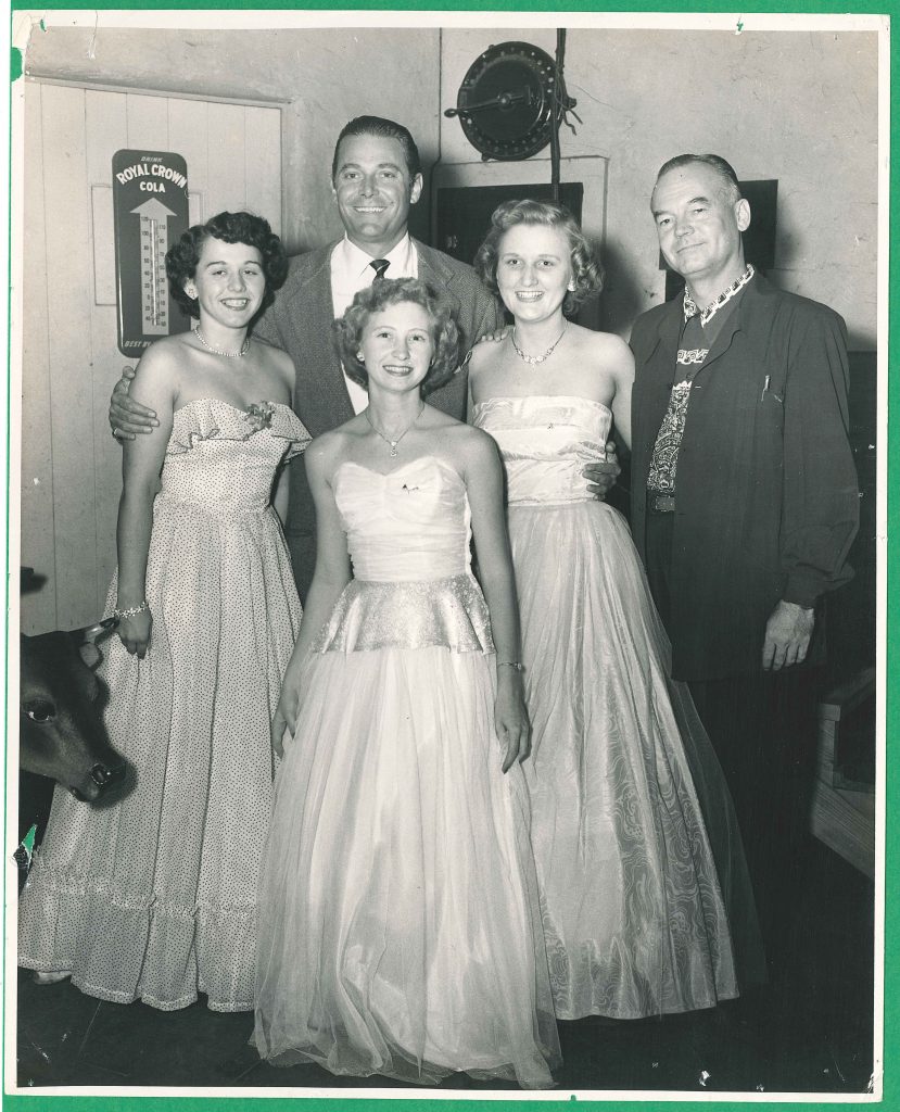 1940s vintage photo of 3 college students in 1940s evening dresses for a college dance posing with 2 older men. Stunning 1940s Fashions and 1940s Hairstyles on dispaly.