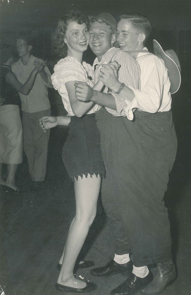 1950s vintage photo of two young men and one young woman in costumes dancing together at a1952 Sadie Hawkins dance at Palm Beach Junior College in 1952. 