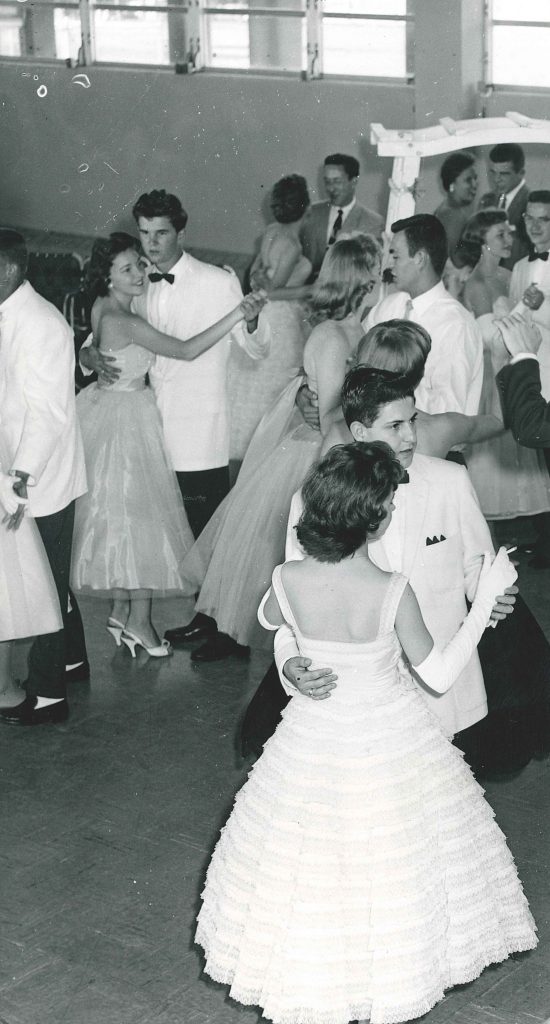 1950s vintage photo of a college dance - 1950s Prom or 1950s Homecoming featuring young women in 1950s dresses and men in tuxedos. 