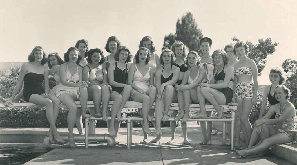 1950s vintage photo of women college students at the pool in 1950s swimsuits and 1950s hairstyles in palm beach junior college