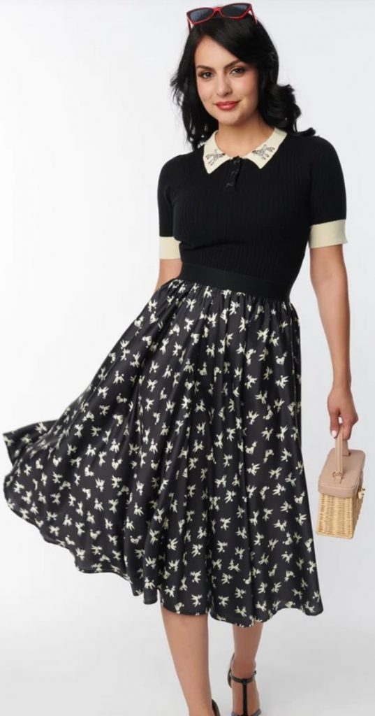 Unique Vintage Black Poodle Print Hilty Midi Skirt. An adorable midi skirt, crafted in a lightweight satin-like fabric that dances with leaping white poodles against a black backdrop. Complete with an elastic banded waist.