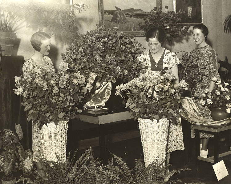 1930s vintage photo of Women inspect rose exhibit in the Horticulture Building at the Chicago Worlds Fair 1933 1934. The Women are in 1930s fashions and 1930s Hairstyles. 