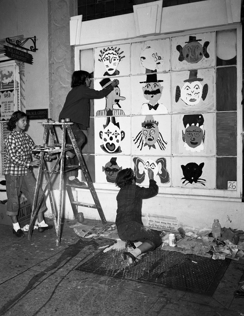 1940s vintage image of three young black teenage girls painting a halloween scene on a business window in Newark, NJ in 1948