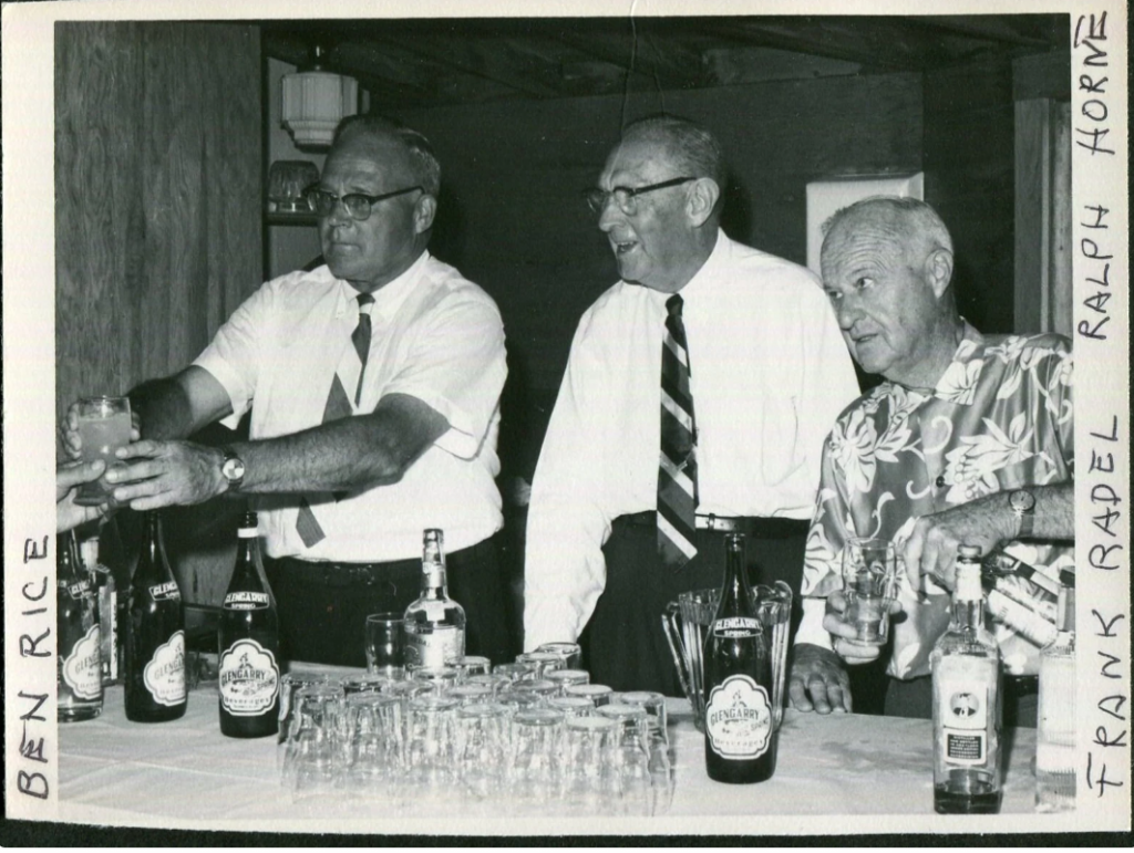 1960s vintage photo of Guys Mixing Drinks Behind the Bar at the Social Club  in the 1960's. The one guy is wearing a hawaiian shirt. 