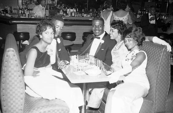 1960s vintage photo of two Black couples all dressed up at a bar in 1960s fashions. They are Members of the Capetowners Club in a bar in the Five Points neighborhood of Denver. (early 1960s)