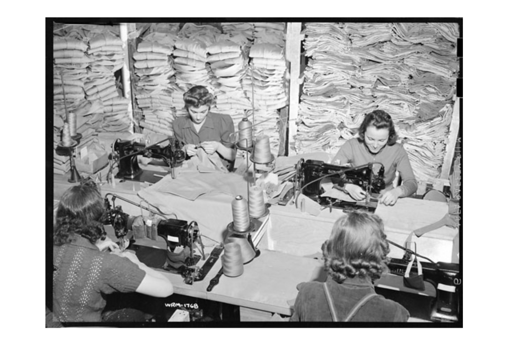 1940s Photo..April 16th, 1942. Women workers stitch service uniforms using sewing machines at the Great Western Garment Co (Edmonton, Alberta).