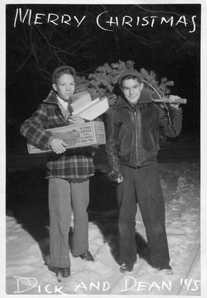 1940s vintage photo / 1940s vintage Christmas card showcasing two boys in 1945 holding a christmas tree and christmas gifts in 1940s winter clothing. 