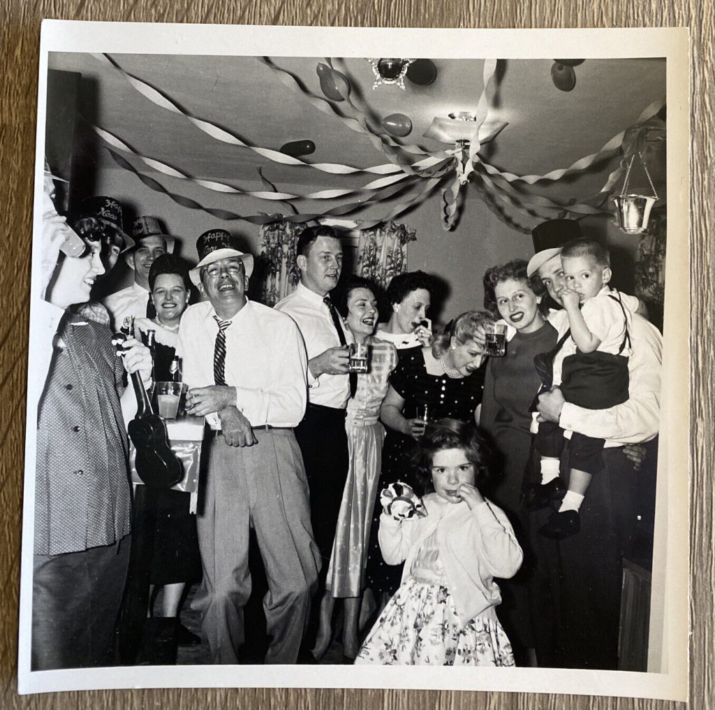 Early 1950s vintage New years eve photo featuring a house party with adults and kids and decoration