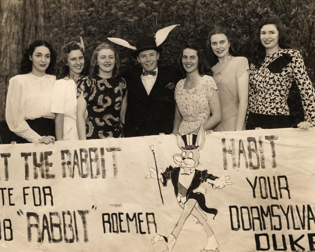 1940s vintage photo from 1948 featuring young women in beautiful 1940s fashions at the University of Wisconsin Madison holding a sign to vote for a guy named rabbit for Dorm Duke (dressed as a rabbit). 