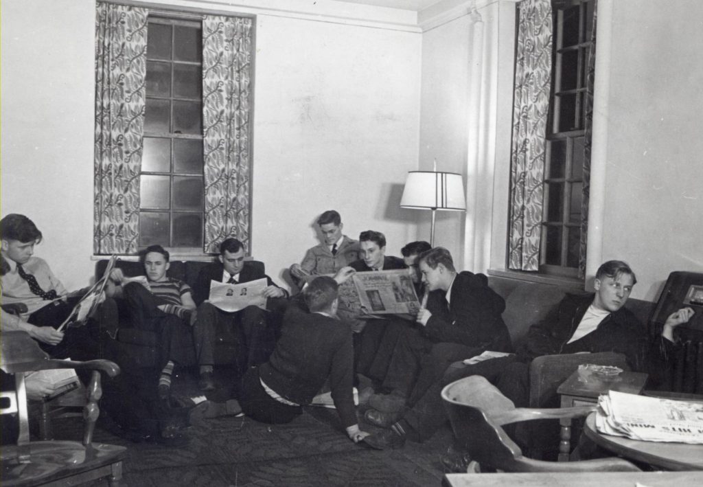 1950s photo of young men in the dorm den reading chatting and listening to the radio at the University of Wisconsin madison.