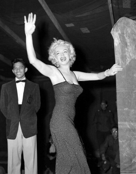 1950s vintage photo of Marilyn Monroe in Korea 1954 in a Ceil Chapman designed purple dress. Marilyn loved the dress so much she asked the designer to make her an identical dress in black.