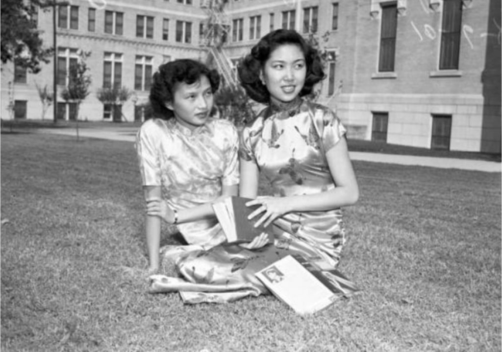 1950s vintage photo of two young women in traditional Chinese dresses on the lawn at a San Antonio College. Mae Wang, left, and Jeanne Chen enjoyed a relaxing afternoon on a lawn at Our Lady of the Lake University. The two attended the university thanks to a four-year scholarship through an overseas student service.