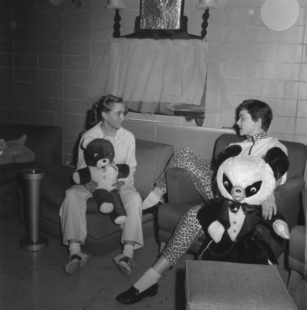 1950s vintage photo of two young university students in 1950s fashions one in saddle shoes another in leopard print (capris pants & leopard print collar sweater) holding giant teddy bears at their residence hall. Vintage Dorm Life in Wisconsin