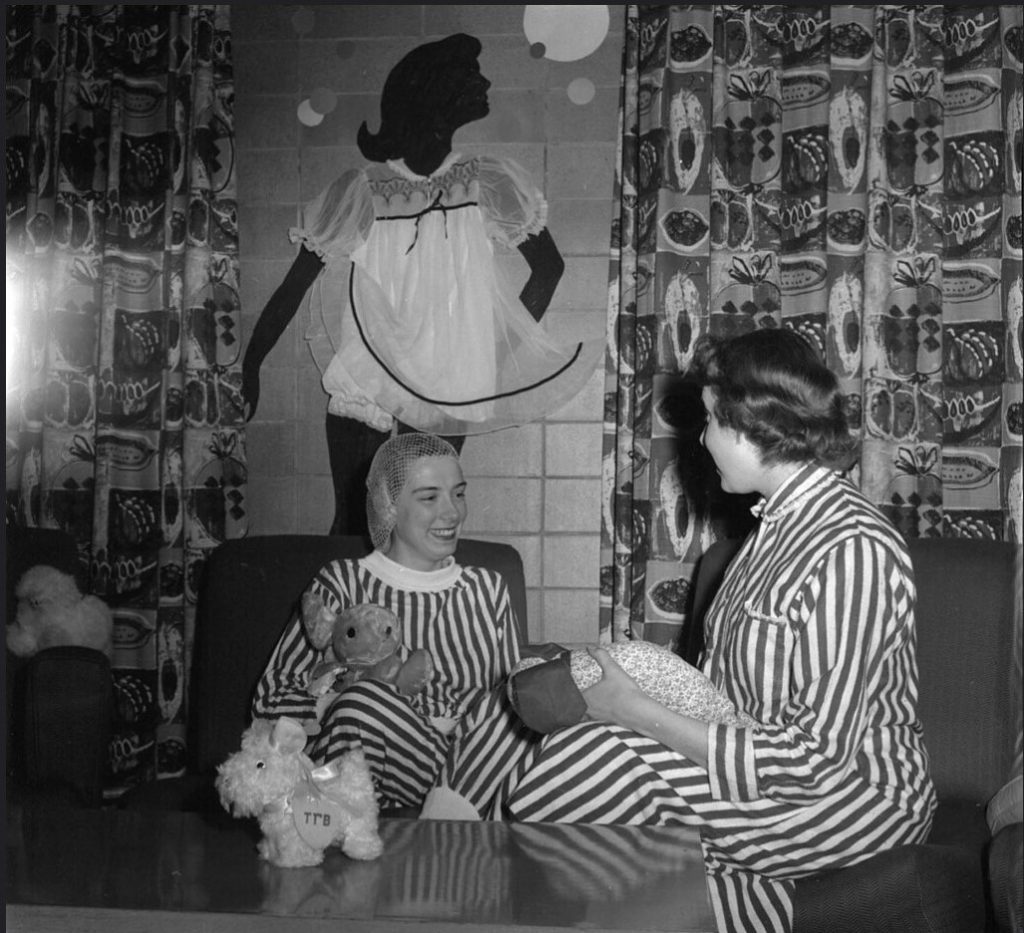 1950s vintage photo of two young women at the university of Wisconsin Madison in striped pajamas in their dorm building having a a slumber party