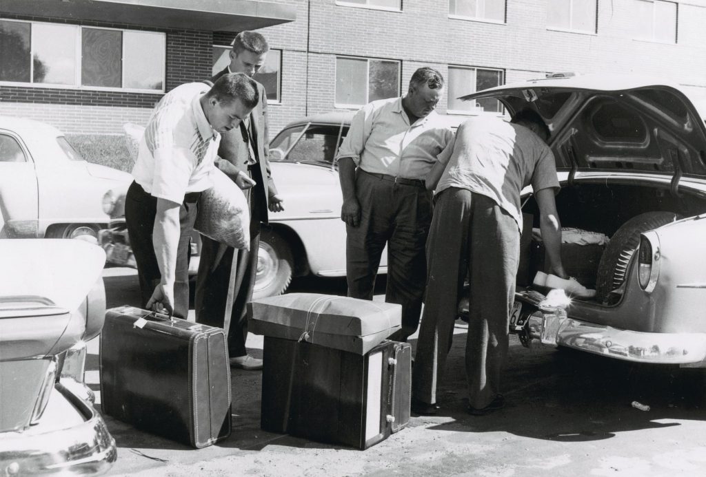 1950s vintage photo of young men in 1955 moving into their Dorms at the University of Wisconsin Madison. 1950s fashion for men  & 1950s cars.