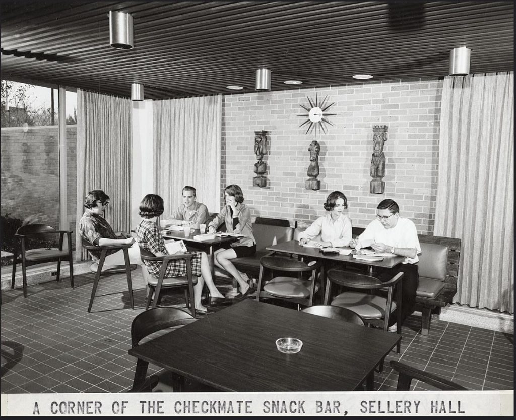 1960s vintage photo of students at the University of Wisconsin Madison relaxing at the snack bar at Sellery Hall. The room is Mid Century with a Tiki feel on the wall