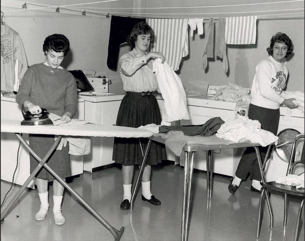 1960s vintage photo of women university students in their dorm at the University of Wisconisn doing the laundry and ironing