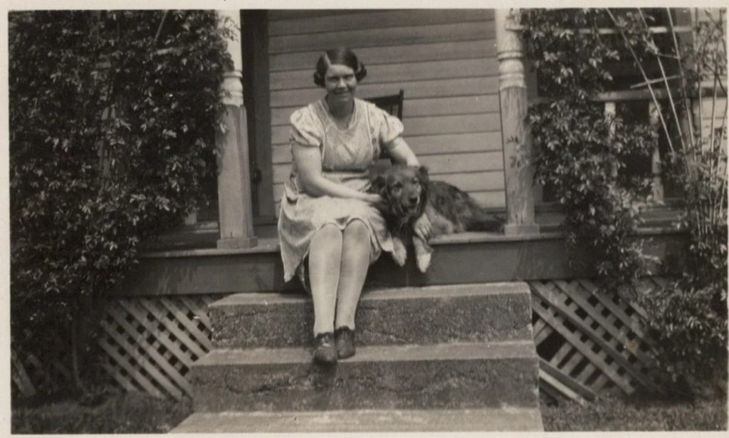 1920s vintage photo of a young woman in 1920s dress and 1920s hairstyle sitting on her front step with her dog