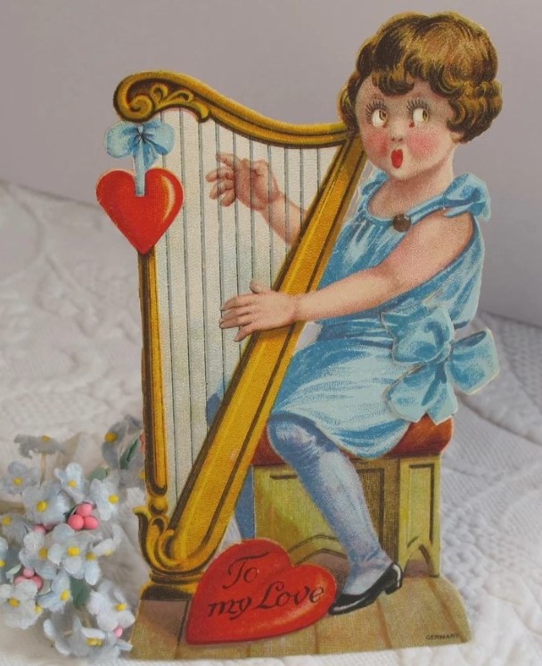 1920s Valentine Card - features a little girl playing a harp. A big red heart reads "To My Love". The girl is dressed in blue with a bow at her waist. The bow moves and causes her eyes to move back and forth