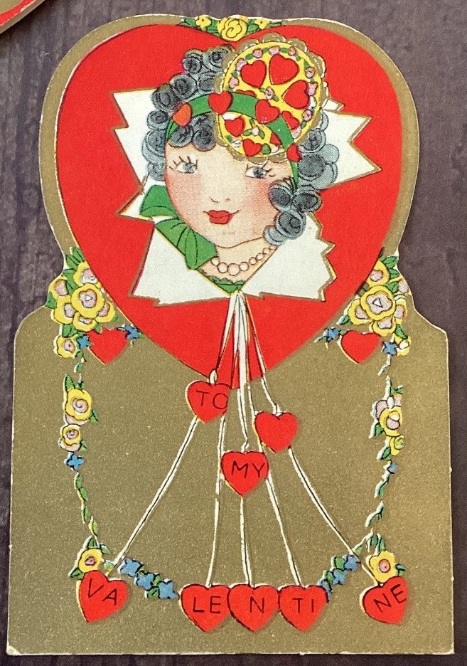 1930s vintage Valentine Card featuring an illustration of a pretty young woman's face with a valentine hair accessory. 