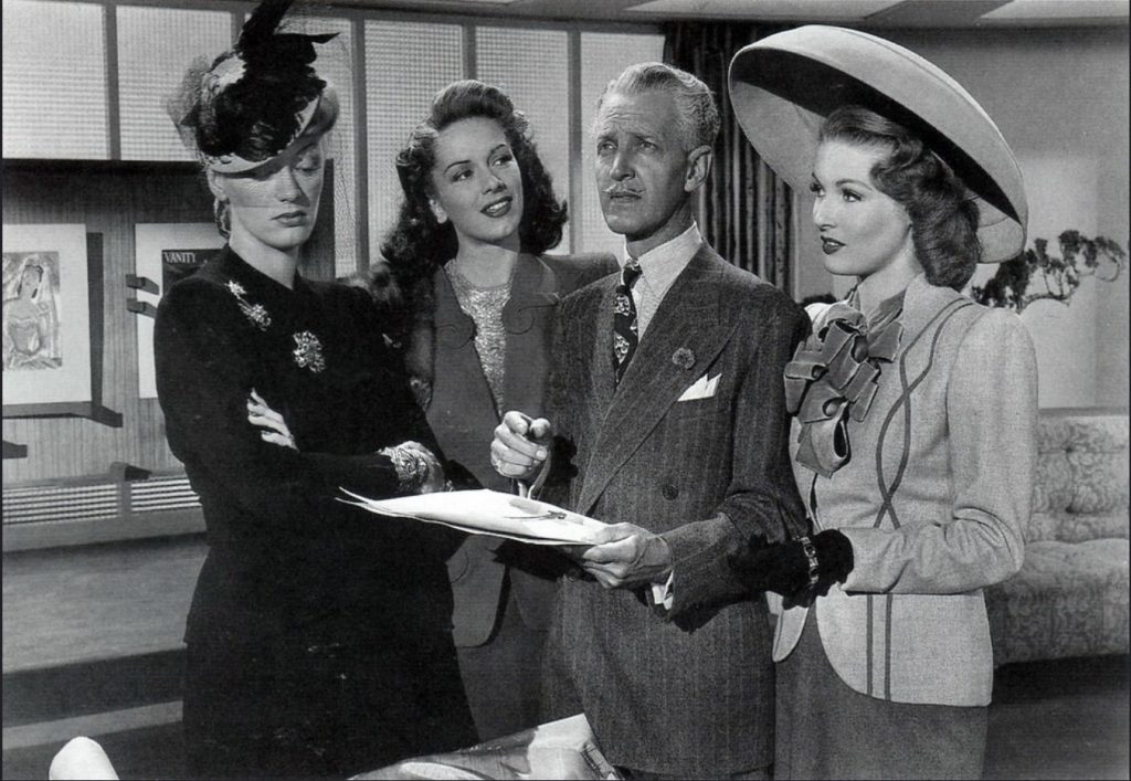 Cover Girl, 1944 screenshot. L-R: Eve Arden, Jinx Falkenburg, Otto Kruger, Anita Colby.