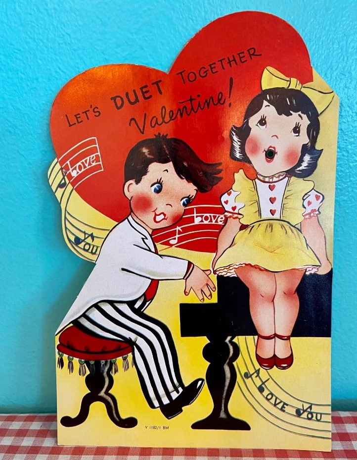 1950s vintage Valentine Card featuring a boy and girl around a piano playing it and singing. 