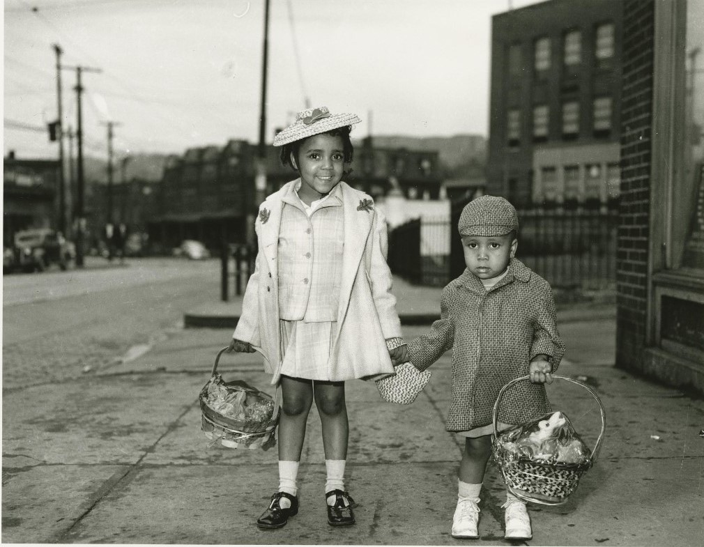 1940s vintage photo of a young Black boy and young Black girl in their Easter clothes holding easter baskets posing for a photo by Charles Teenie Harris 1940-1945. 